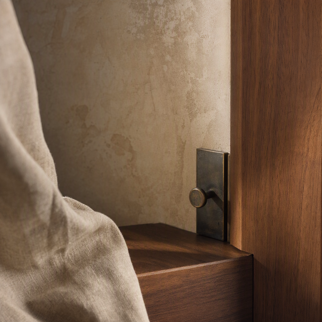 Close material detail of softly textured plaster, walnut timber, and natural linen