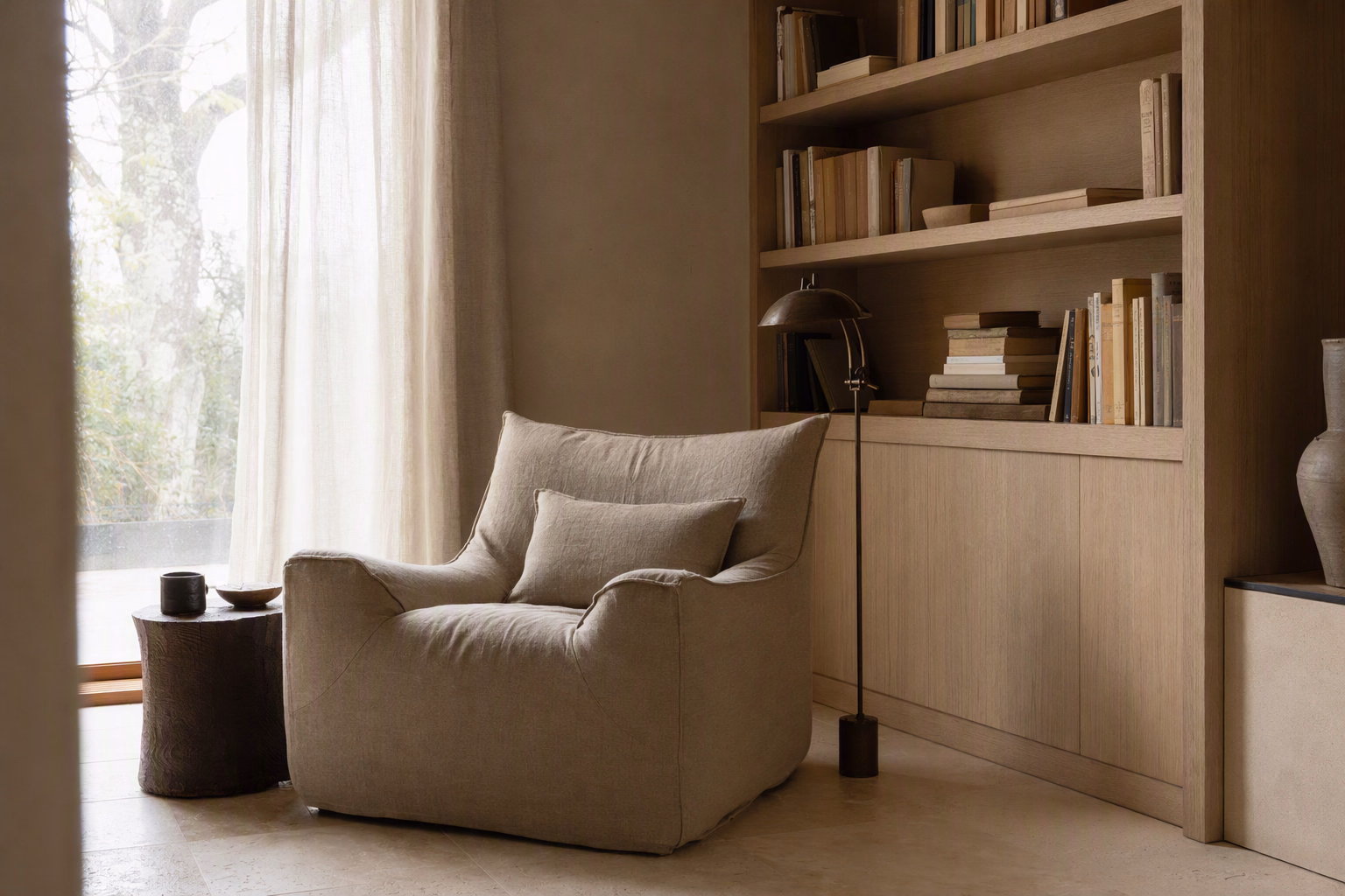 Tall reading corner with linen seating, pale oak shelving, and softly washed limestone walls