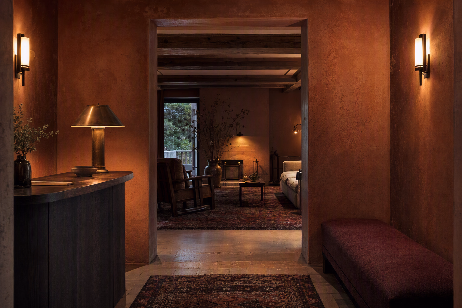 Tall reception threshold in pigmented sienna plaster with a dark oak desk and aged brass lighting